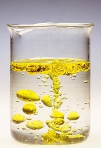 A beaker filled with water to which oil has been added, demonstrating insolubility of oil in water.